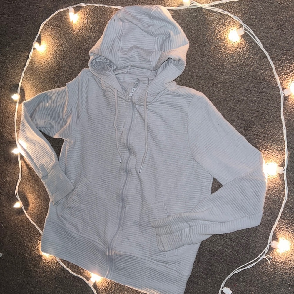Gray zip-up hoodie. It has 2 pockets each inside & out. It has the glove sleeve.